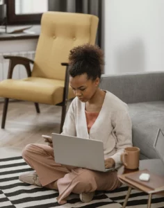 Person sitting on living room floor using their laptop and mobile phone